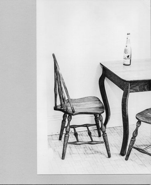 Empty table and chair w wine bottle